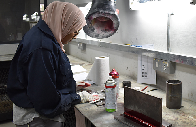 Student removing excess penetrant during a thin pl