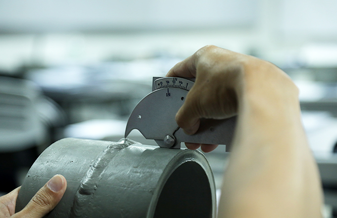 Person measuring the weld reinforcement on a pipe